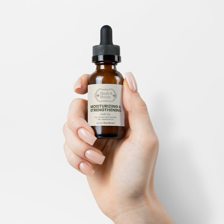 Hand holding Bottle Of Moisturizing & Strengthening Hair Oil By Blush And Bloom Care USA